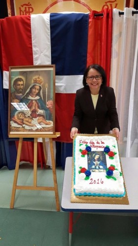 La cónsul Carmen Almonte muestra el pastel dedicado a la Virgen de la Altagracia para la celebración.  