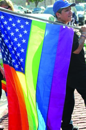 ➥➥ Neida Pérez sostiene la bandera multicolor durante la vigilia en el parque Campagnone de Lawrence en memoria de las victimas de Pulse Nightclub en Orlando, Florida.