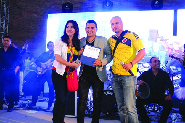 ➥➥ Gladys Ortiz entrega certificado honorífico de la Fundación FELVU a Jorge Celedón. Los acompaña el presidente del Festival Alejandro Magno