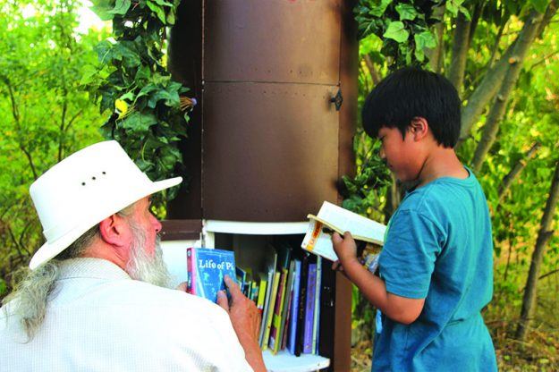 ➥➥ Wayne Hayes le enseña uno de los libros a Tristan Namen de la Biblioteca Libre, localizada en Jacques Pond en la calle Genesee al sur de Lawrence.
