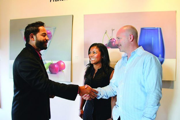 ➥➥ El pintor Francisco Collado saluda a Gary Sidell, propietario de Bell Tower Management y a Janin Durán directora del programa hispano de EforAll.