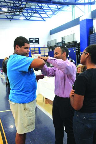➥➥ Marcus Maldonado, de 17 años de edad recibe un chequeo médico por el doctor. Raman Nohra de Greater Lawrence Family Health Center durante la feria de trabajo en la Escuela Superior de Lawrence.