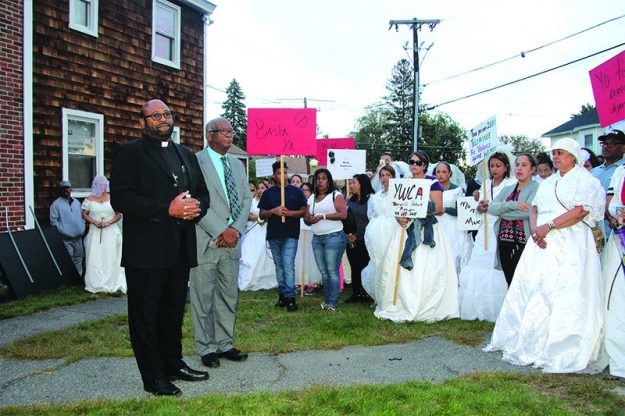 ➥➥ Los ministros Joel Almonó y Victor Jarvis hacen una oración en frente de la casa de la difunta Wanda Rosa en Methuen como parte de la Marcha de las Novias.