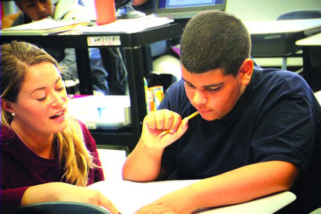 ➥➥ La maestra de séptimo grado Blake Orban ayuda a Rudy Guzmán durante una clase de matemáticas en la Spark Academy, parte de la escuela South Lawrence East School.