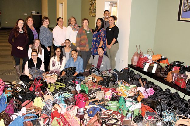 Empleados de Elder Services of Merrimack Valley posan junto con las 355 bolsos y mochilas que colectaron.