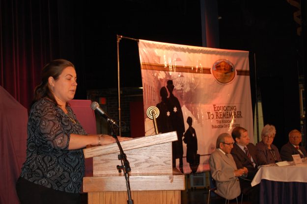 La Directora de Educación de las Naciones Unidas en Boston, Caitlin Moore, le habla a los estudiantes. En el panel estaban la Superintendente de las Escuelas Públicas, Catherinna Latham, los dos sobrevivientes del holocausto, el director del Comité Judío Americano, Robert Leikind y el Jefe de la Sección en Derechos Civiles de la Oficina de la Fiscal General, Jonathan Miller.