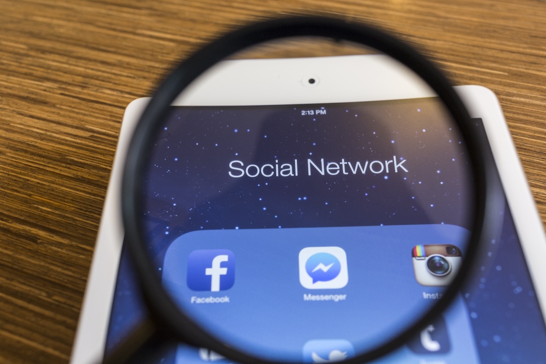 All of popular social media icons on tablet device screen with magnify glass.